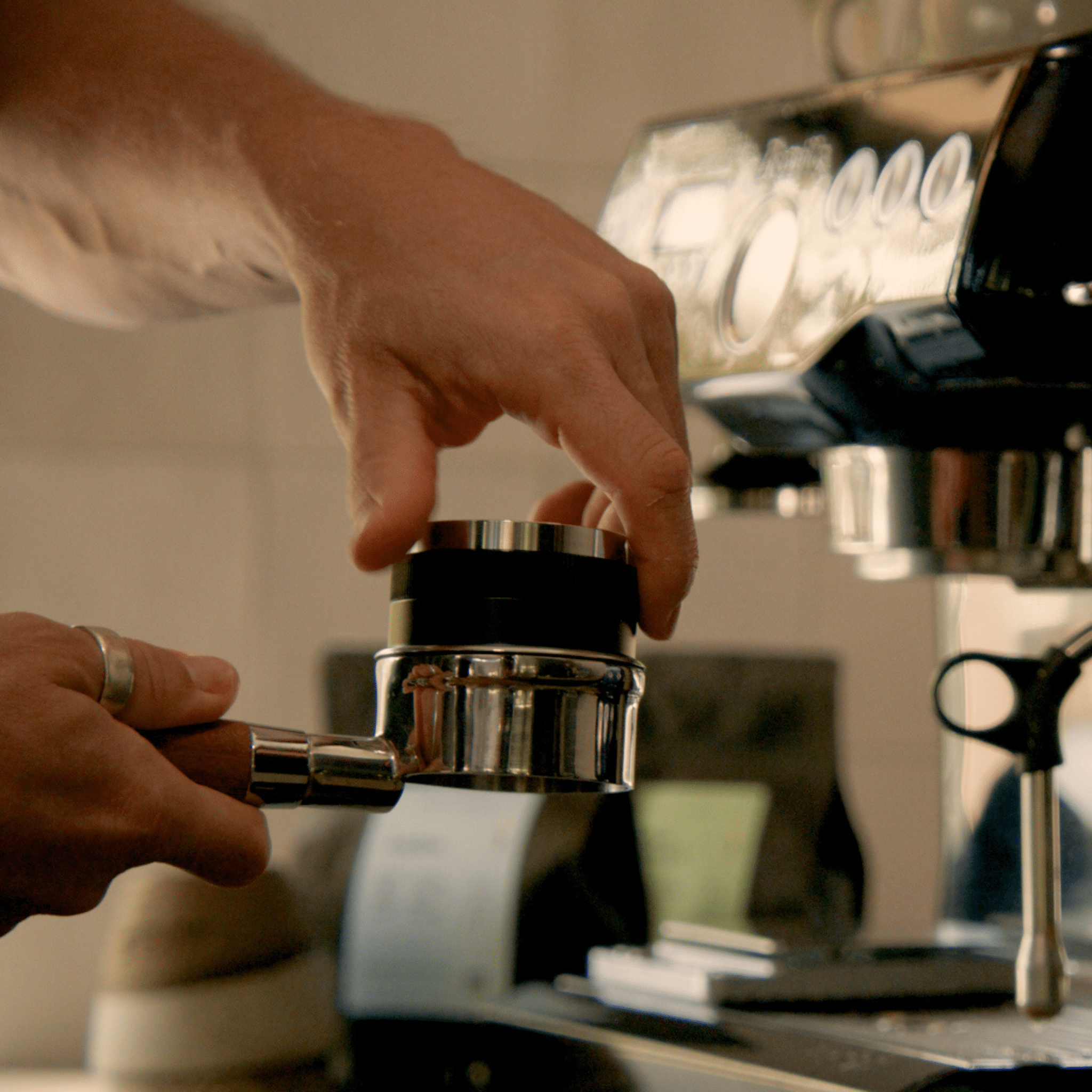 Adjustable 2-in-1 coffee tamper and distributor on a benchtop